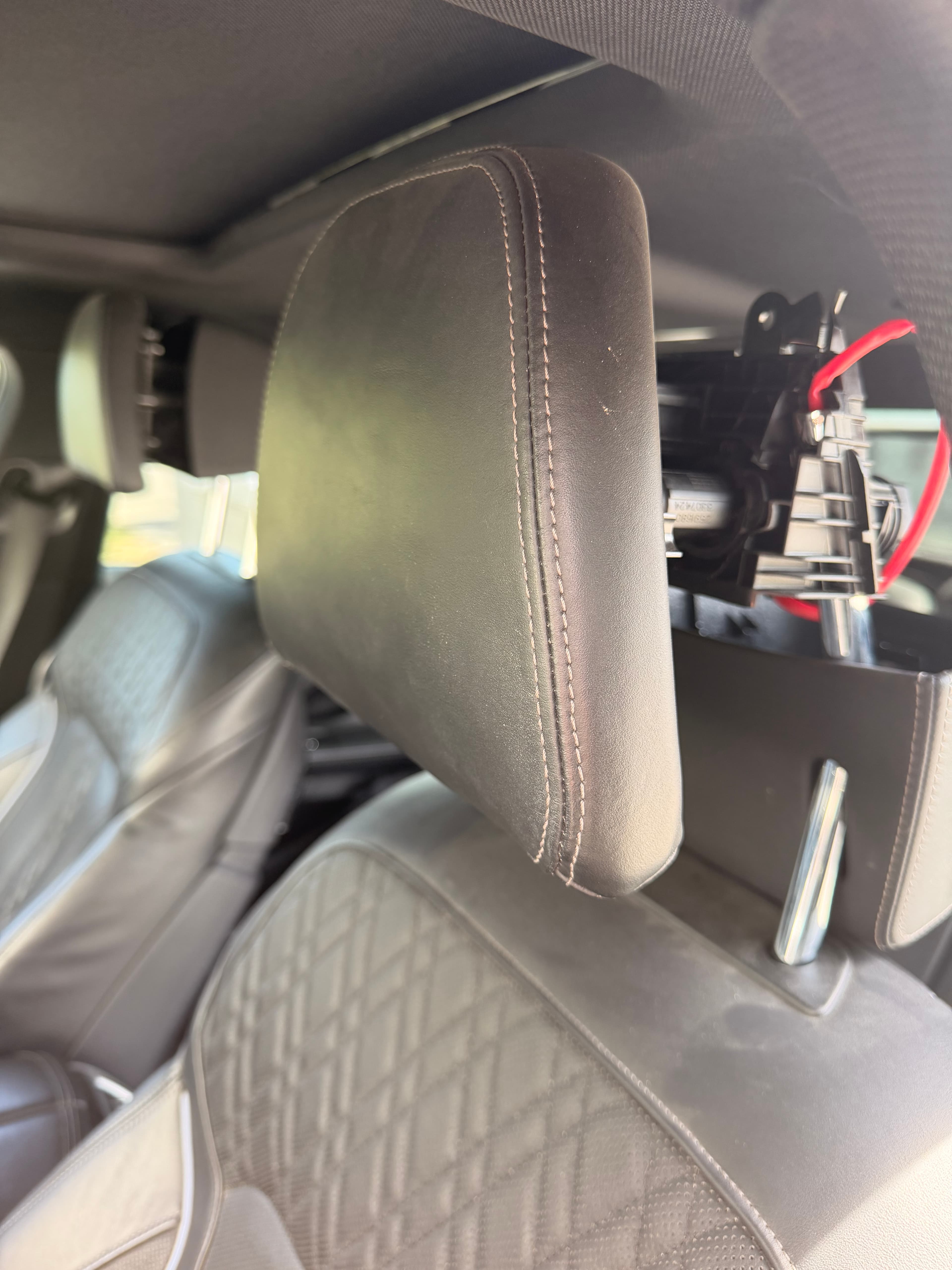 Wnętrze kabiny BMW G12 podczas Sesji 2 — przygotowanie do demontażu aktywnych zagłówków, widoczny fragment fotela M Sport i kabel diagnostyczny